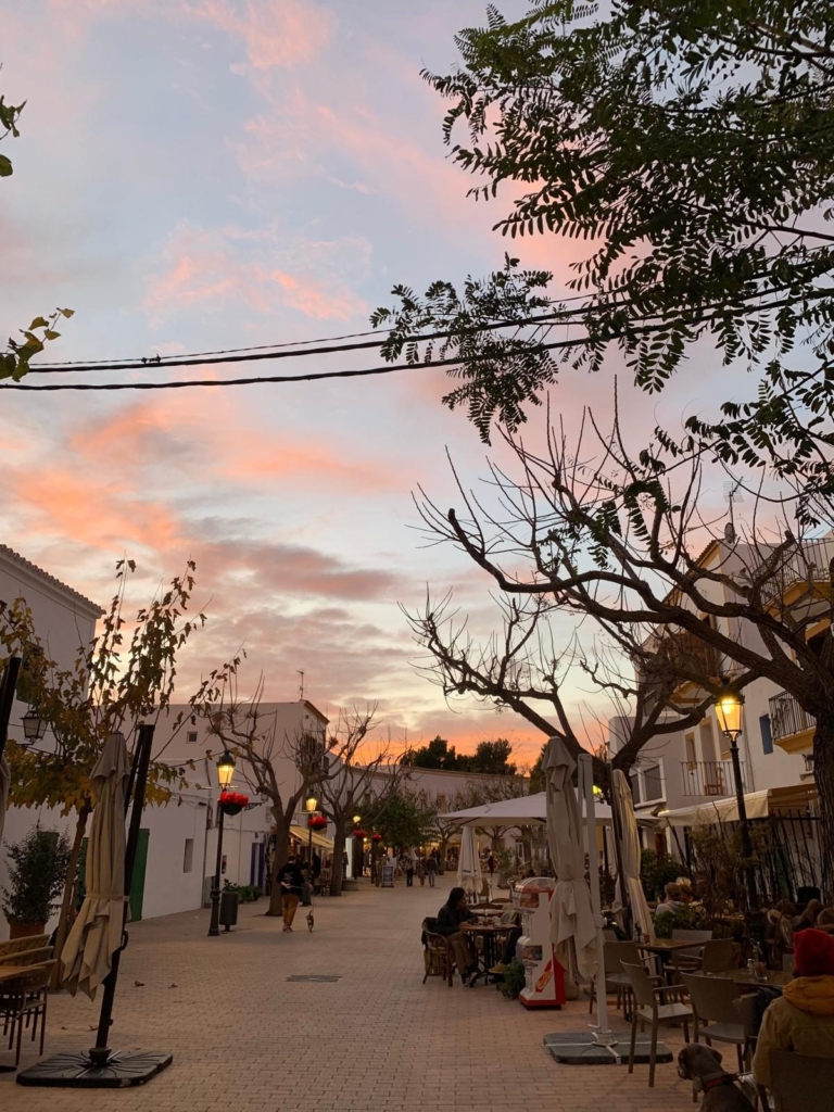 Autumn sunset with a pink sky over a street with café terraces in an Ibizan village